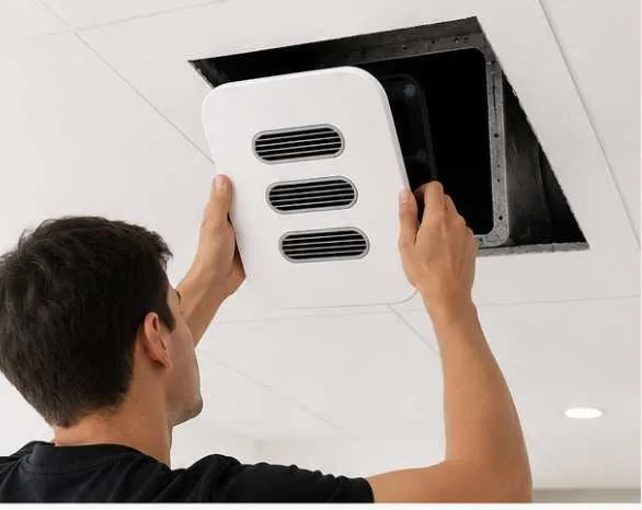 A person lifting an airable faceplate into an open ceiling duct by hand